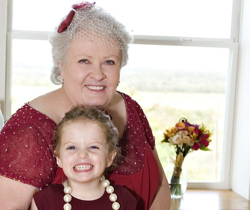 Grand mère avec sa petite fille sur les genoux toutes les deux sur un canapé