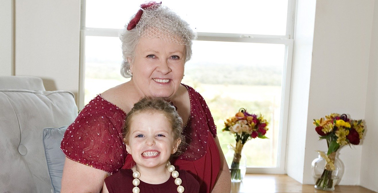 Grand mère avec sa petite fille sur les genoux toutes les deux sur un canapé
