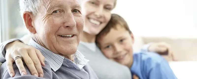 Photo d'un senior assis sur le canapé avec sa fille et son petit fils
