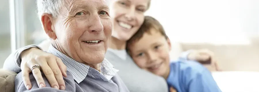 Photo d'un senior assis sur le canapé avec sa fille et son petit fils