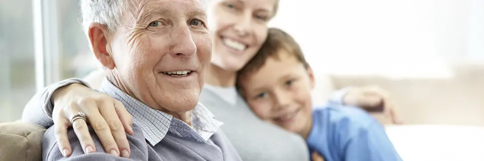 Photo d'un senior assis sur le canapé avec sa fille et son petit fils