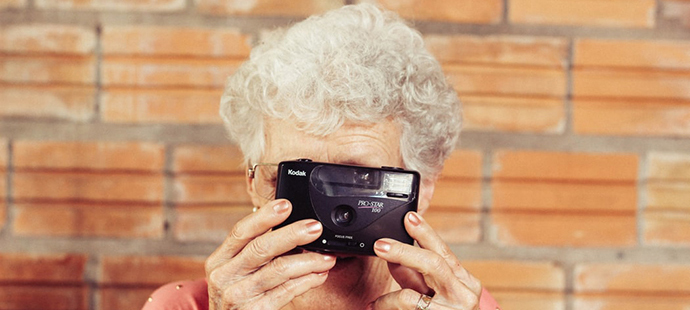 Femme senior tenant un appareil photo jetable devant son visage