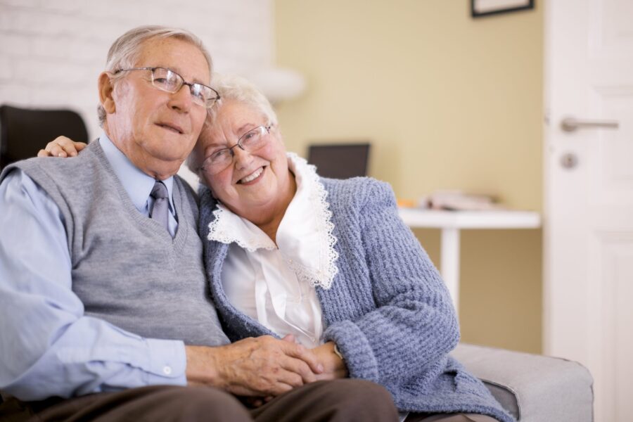 Image d'un couple senior assis sur le canapé qui se tient la main et qui se fait une accolade