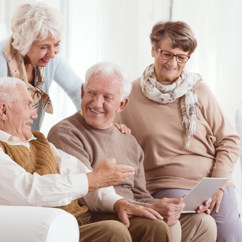 Groupe de senior assis sur le canapé entrain de regarder un ordinateur portable