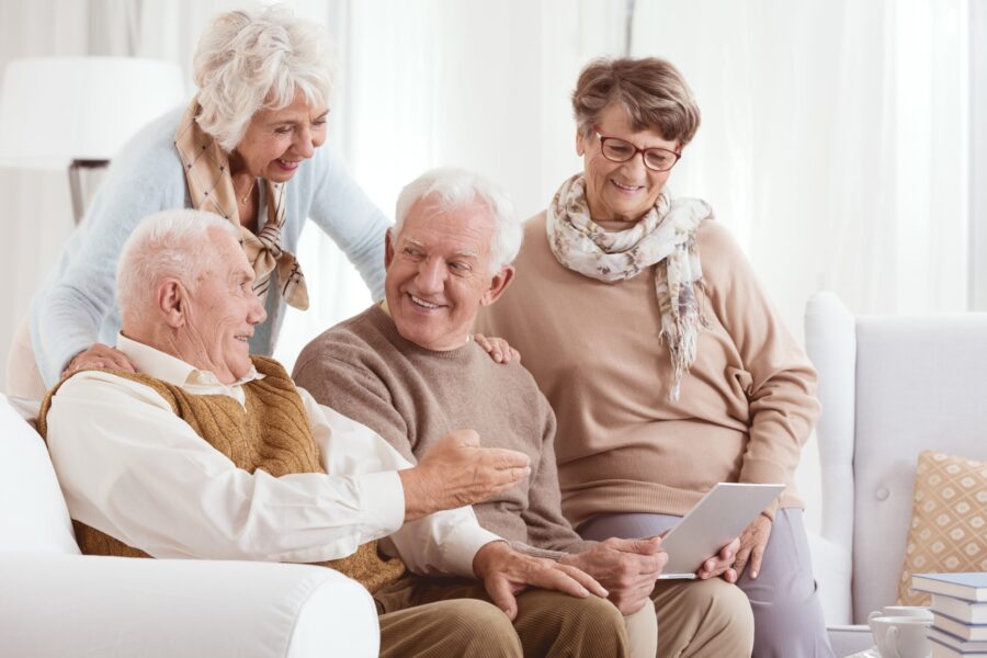 Groupe de senior assis sur le canapé entrain de regarder un ordinateur portable
