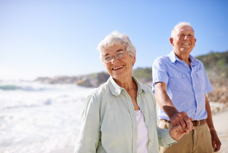 Couple senior marchant main dans la main sur la plage