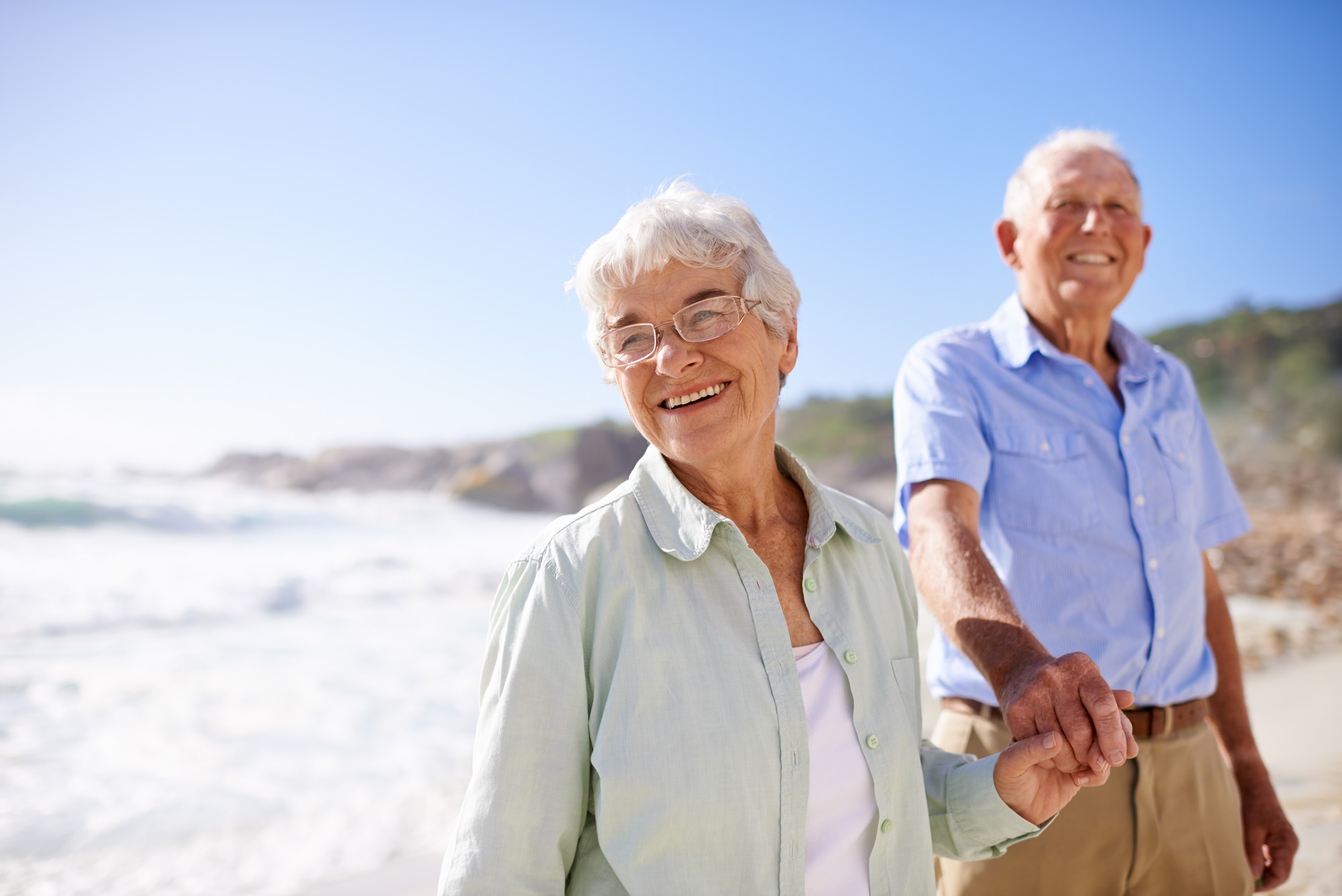 Couple senior marchant main dans la main sur la plage