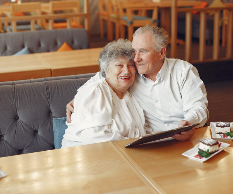 Couple senior en sécurité l'un contre l'autre regardant la tablette et mangeant un dessert