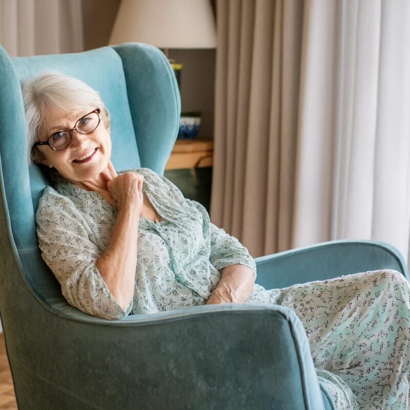 Femme senior assise sur un fauteuil souriant dans son salon