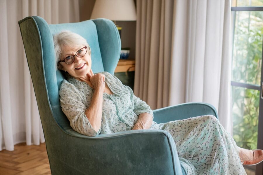 Femme senior assise sur un fauteuil souriant dans son salon