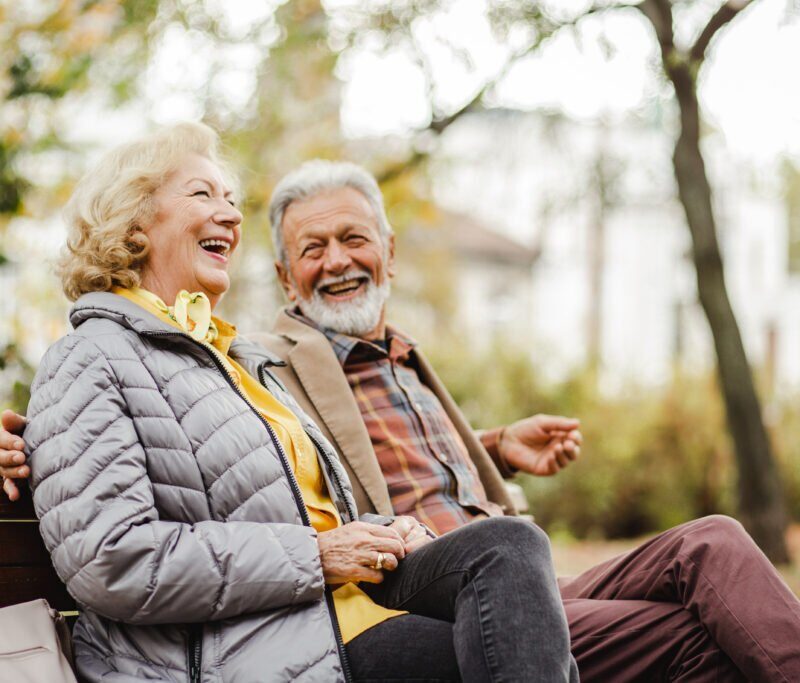Photo d'un couple senior sur un banc rigolant